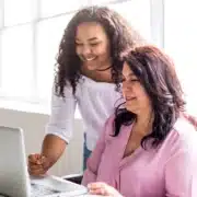 Free Mock Tests Two women reviewing test results on a laptop for exam prep.